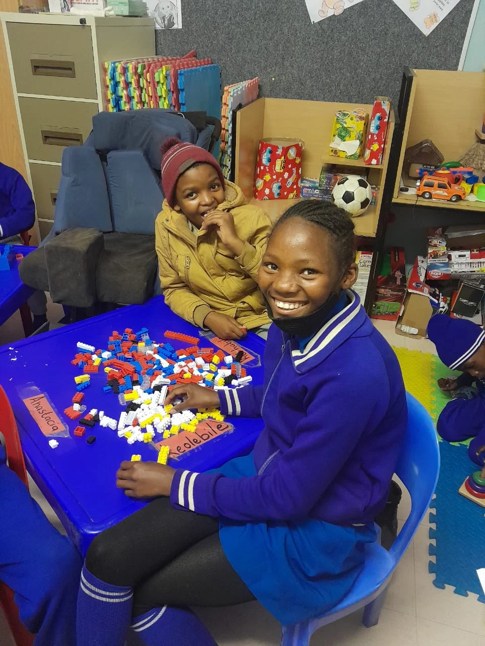 Children exploring colourful building pieces at a classroom table.